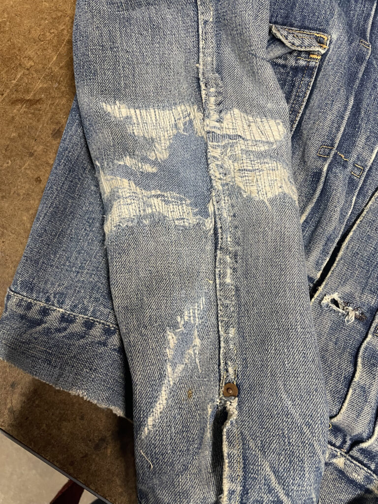 Visible mending on a denim jacket's sleeve